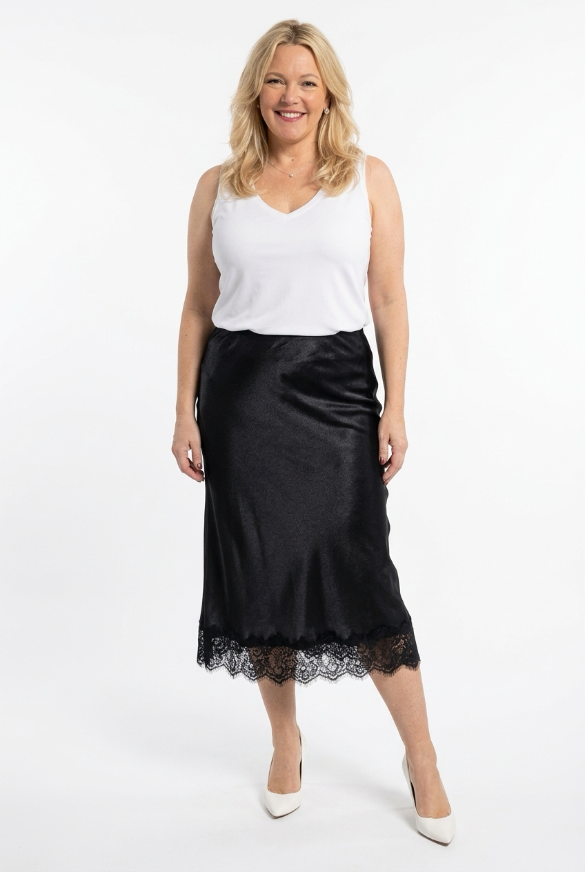 musta satiinihame polven alle pituudella, jossa helmapitsi. Naisen päällä valkoisen paidan kanssa.