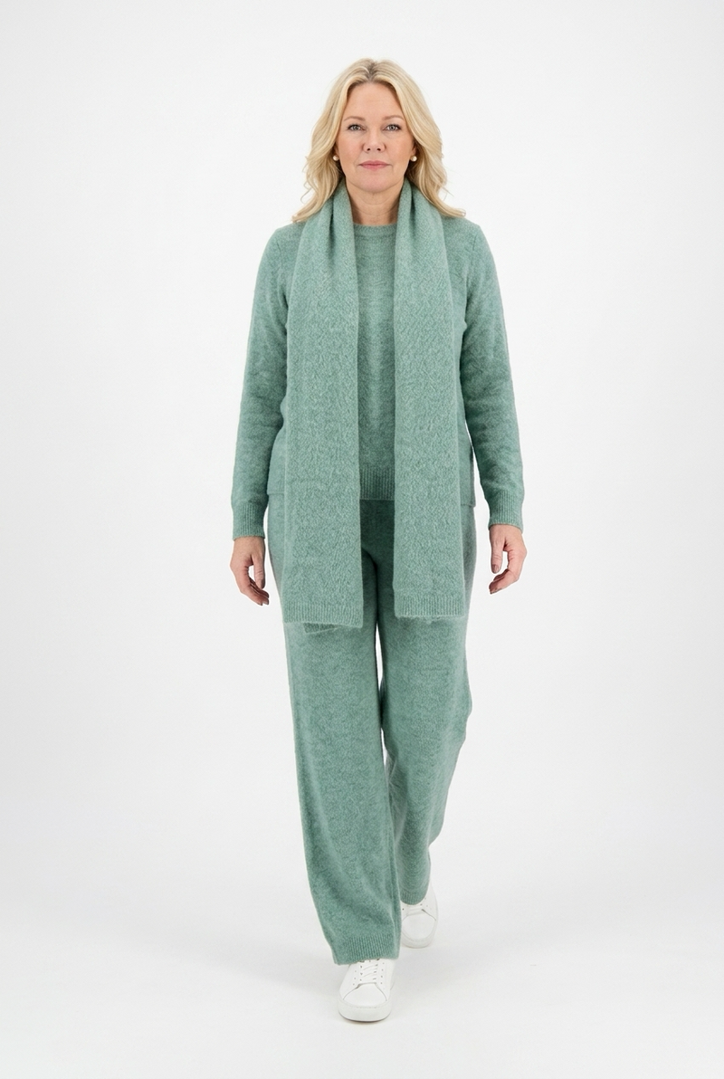 vihreä reilu neulehuivi naisen päällä vihreän neuleasun kanssa.