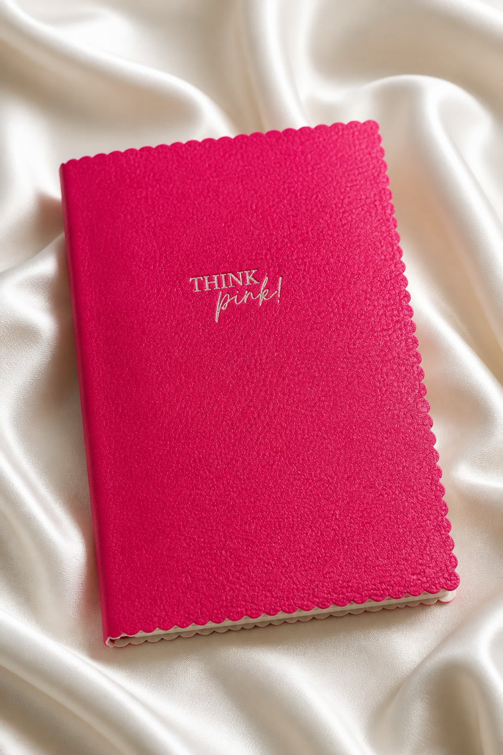 pinkki muistikirja, jossa piparireunat ja hopeanvärinen think pink teksti.