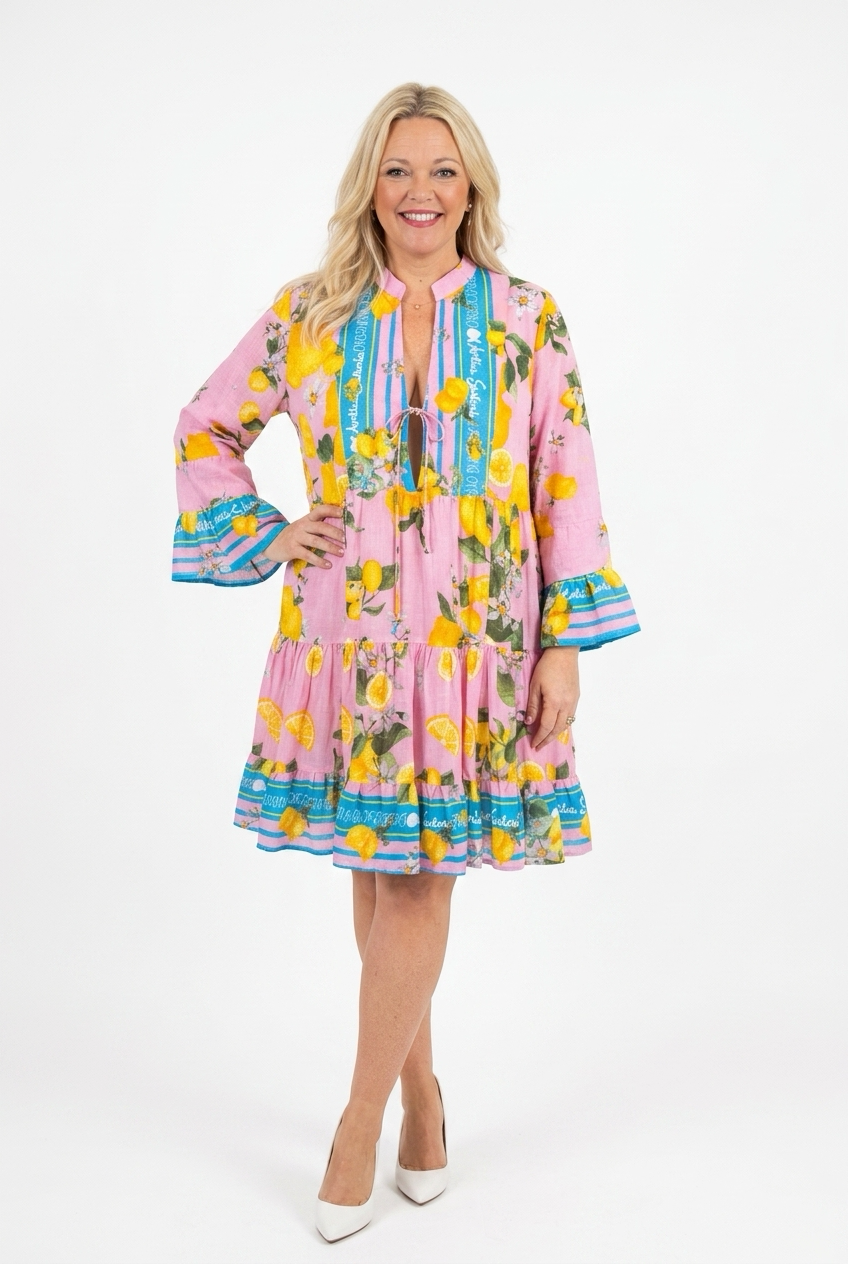 vaaleanpunainen lyhyt ja kellohelmainen mekko, jossa frillahihat ja frillahelma naisen päällä. Mekossa sitruunakuosia ja turkoosin väristä raitaa. Mekko avoin edestä ja siinä nyörit.
