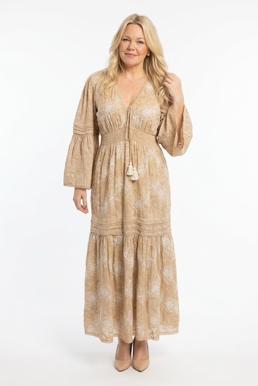 maxipituinen ja pitkähihainen beige mekko, jossa kapea vyötärö, levenevä helma sekä hihat. 