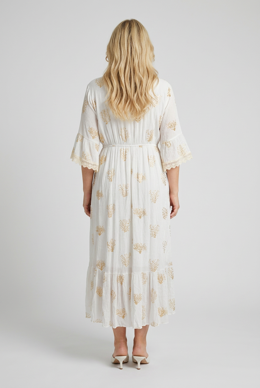 vaalea pitkä bohotyylinen mekko naisen päällä', jossa kullanvärisiä korallinmuotoisia kuvioita, 3/4 hihat.