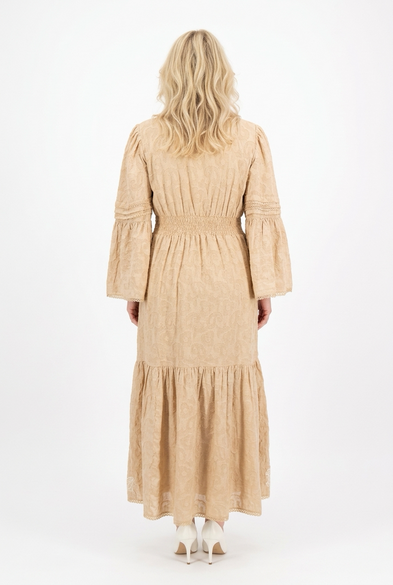 maxipituinen ja pitkähihainen beige mekko, jossa kapea vyötärö, levenevä helma sekä hihat. 