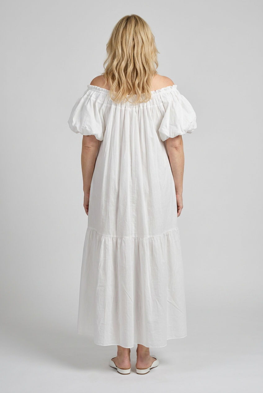 valkoinen maxipituinen ja a-linjainen mekko naisen päällä, jossa lyhyt pussihiha sekä rypytystä pääntiellä.