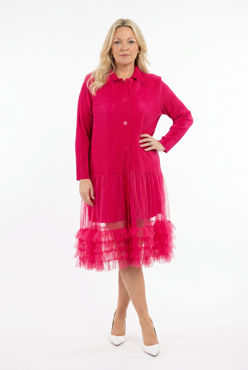 naisen päällä fuksian värinen ja pitkähihainen paitajakku, jossa napitus edessä ja helmaosa tylliä.