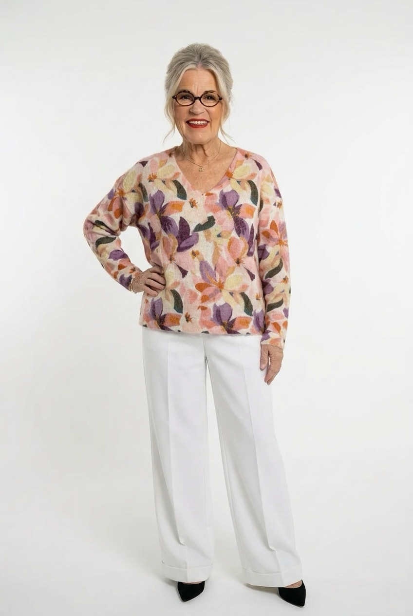 v-aukkoinen, pitkähihainen ja  värikäs kuviollinen neulepusero naisen päällä valkoisten housujen kanssa.