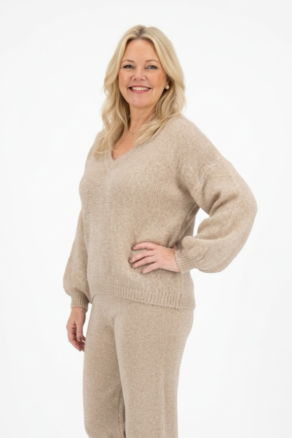 vaalea v-aukkoinen ja pitkähihainen neulepusero naisen päällä.