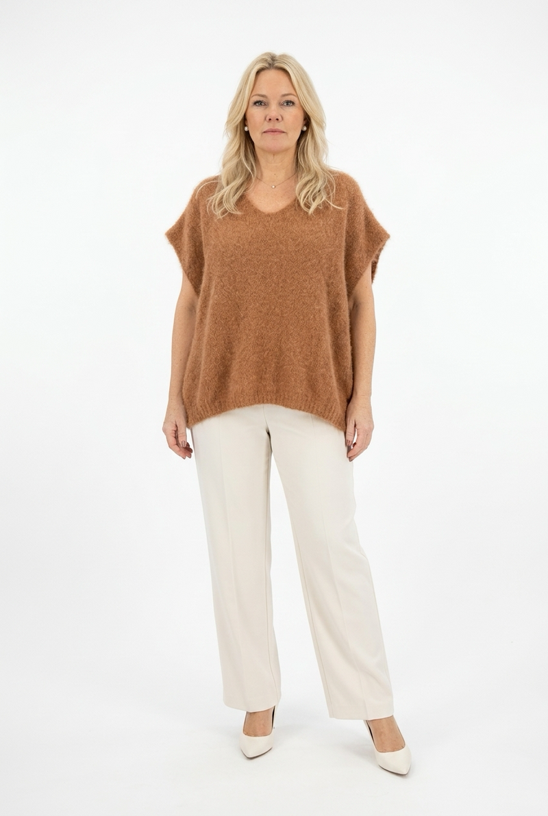 lyhyt kamelinvärinen reilu neulepusero, jossa v-pääntie naisen päällä.