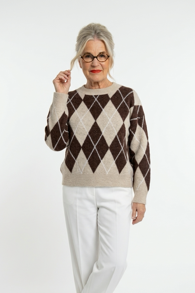 Beige-ruskea salmiakkiruutuinen lyhyt neulepusero, jossa o-aukko ja pitkät hihat naisen päällä valkoisen housun kanssa.