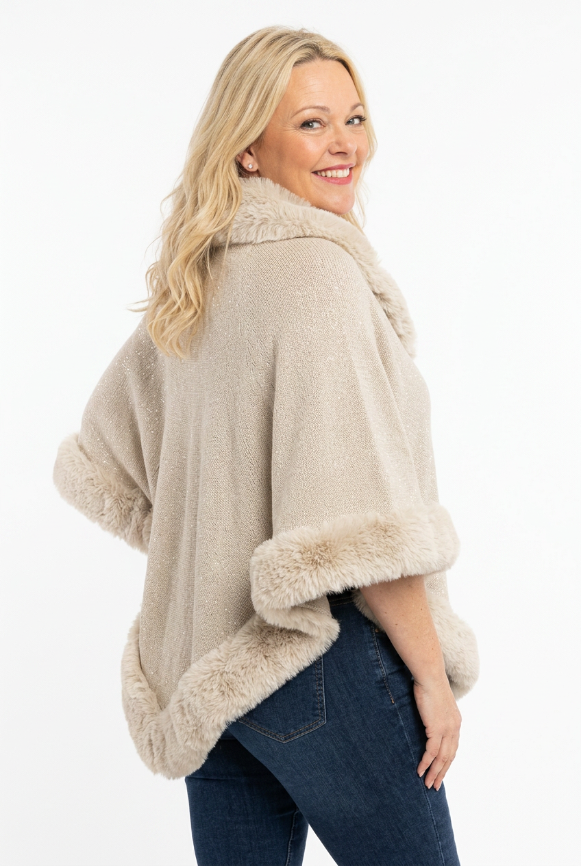  naisen päällä reilu beige poncho, jossa karvareuna ja karvapääntie.