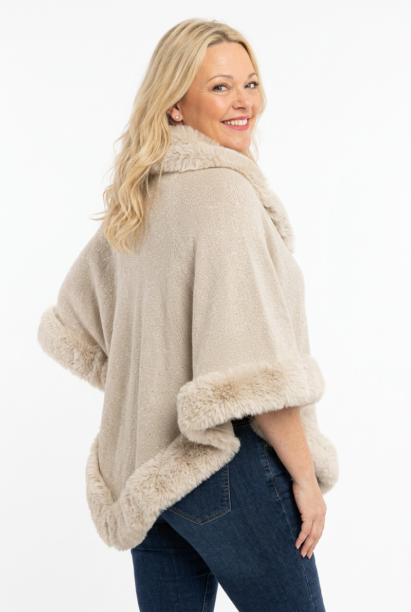  naisen päällä reilu beige poncho, jossa karvareuna ja karvapääntie.