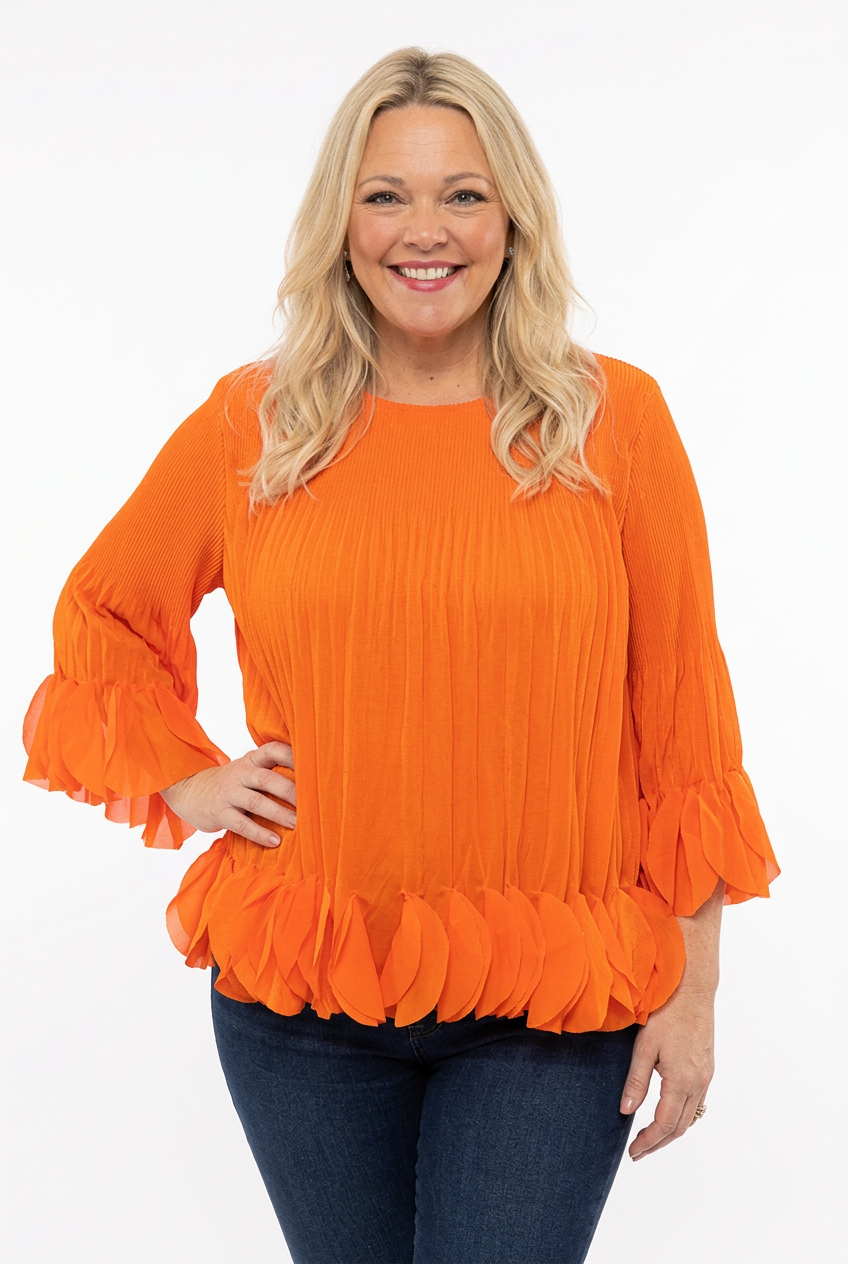 naisen päällä edestä kuvattuna oranssi pliseerattu pusero, jossa o-pääntie, vajaamittainen hiha ja a-linjainen malli. Helmassa ja hihansuussa kolmiulotteisia kangaspyörylöitä.