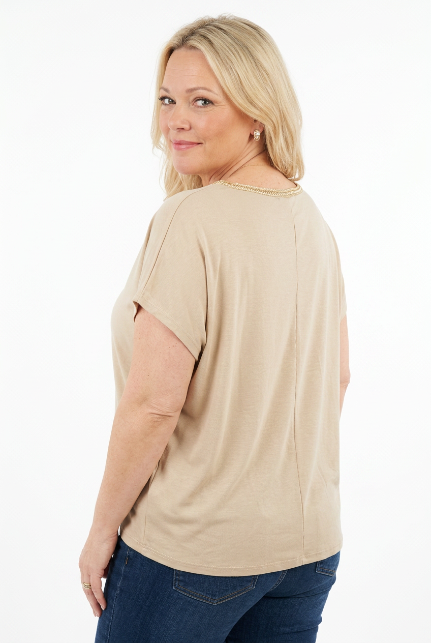beige, väljä ja lyhythihainen tunikapusero, jossa v-pääntie ja koristekuvioita edessä naisen päällä.