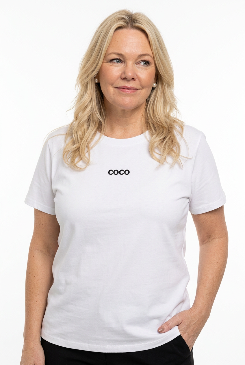 naisen päällä valkoinen t-paita lyhyellä hihalla ja o-pääntiellä, jossa pieni tumma coco logo edessä.