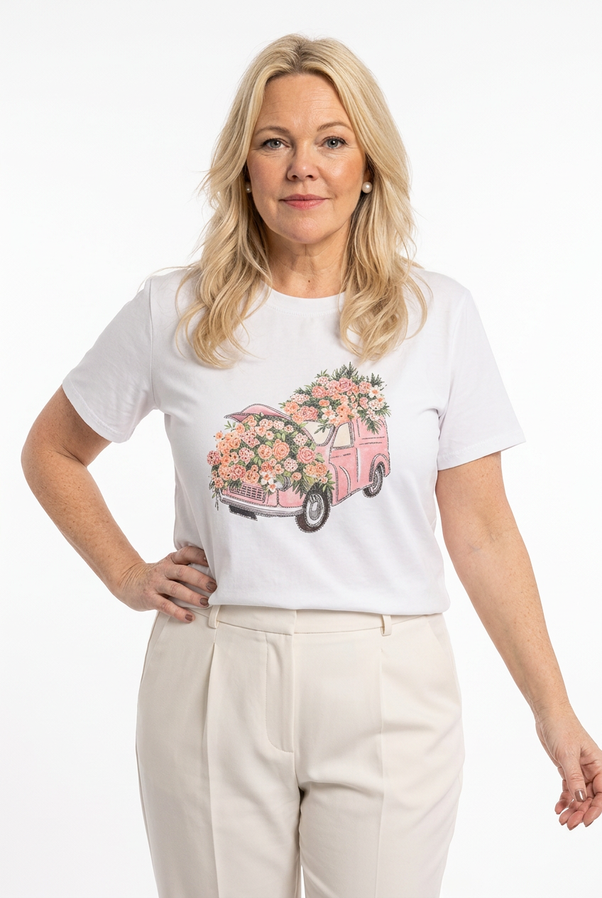 naisen päällä valkoinen t-paita lyhyellä hihalla ja o-pääntiellä, jossa kuvana  roosa auto sekä kukkia koristeltuna strasseilla edessä.