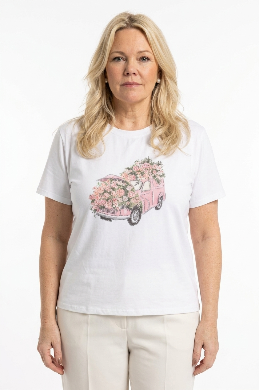 naisen päällä valkoinen t-paita lyhyellä hihalla ja o-pääntiellä, jossa kuvana  roosa auto sekä kukkia koristeltuna strasseilla edessä.