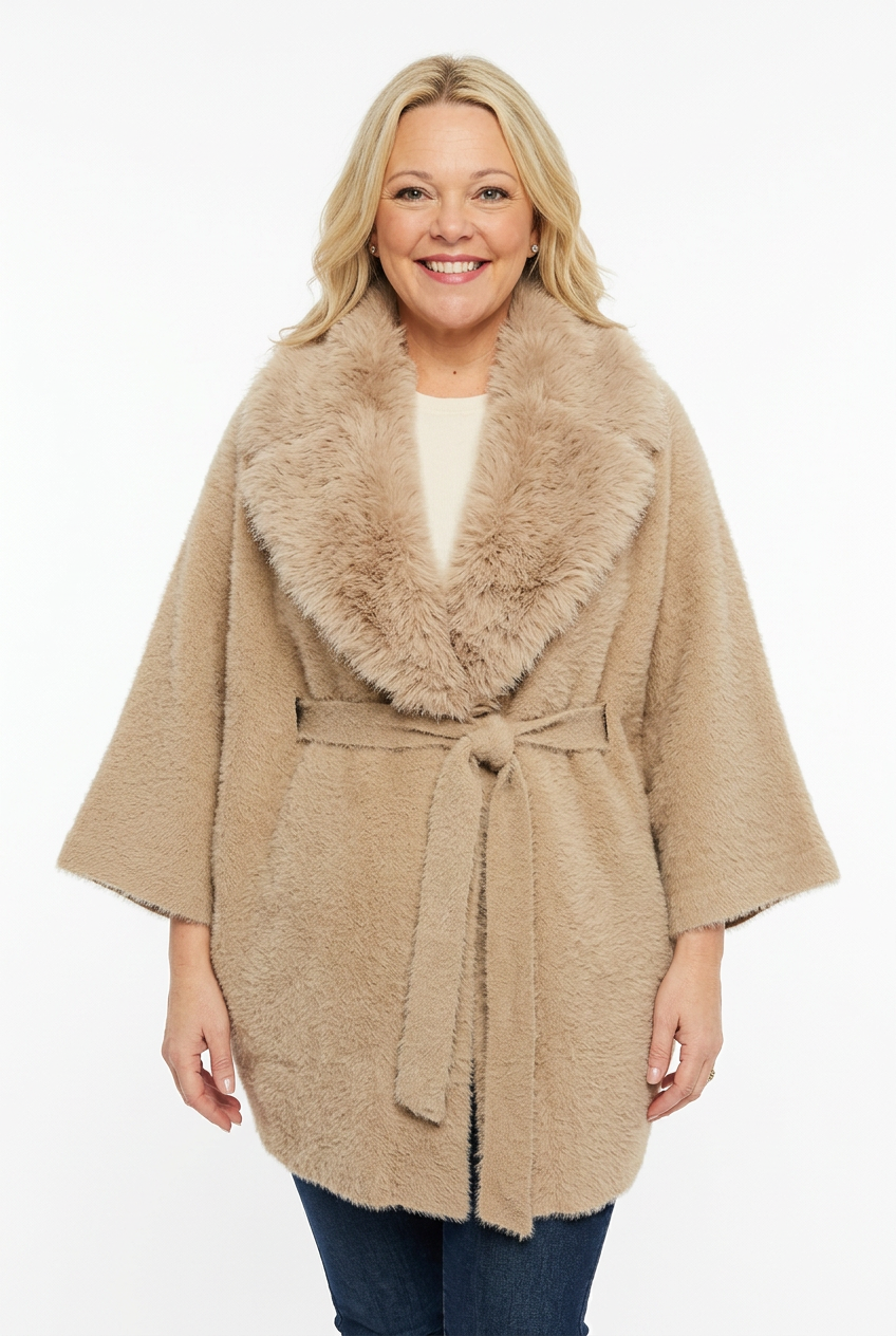 naisen päällä beige lantiopituinen takki, jossa karvakaulus, vajaamittainen hiha ja vyö.
