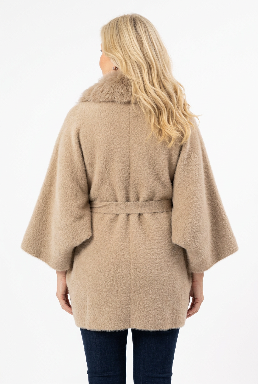 naisen päällä beige lantiopituinen takki, jossa karvakaulus, vajaamittainen hiha ja vyö.
