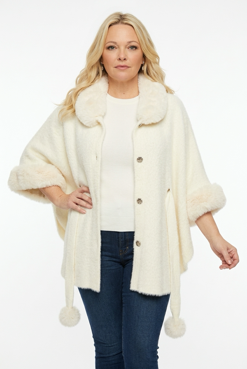 naisen päällä edestä kuvattuna vaalea viittamainen takki, jossa vajamittaiset hihat ja kangasvyö. takissa karvaa hihasuussa ja kauluksessa.